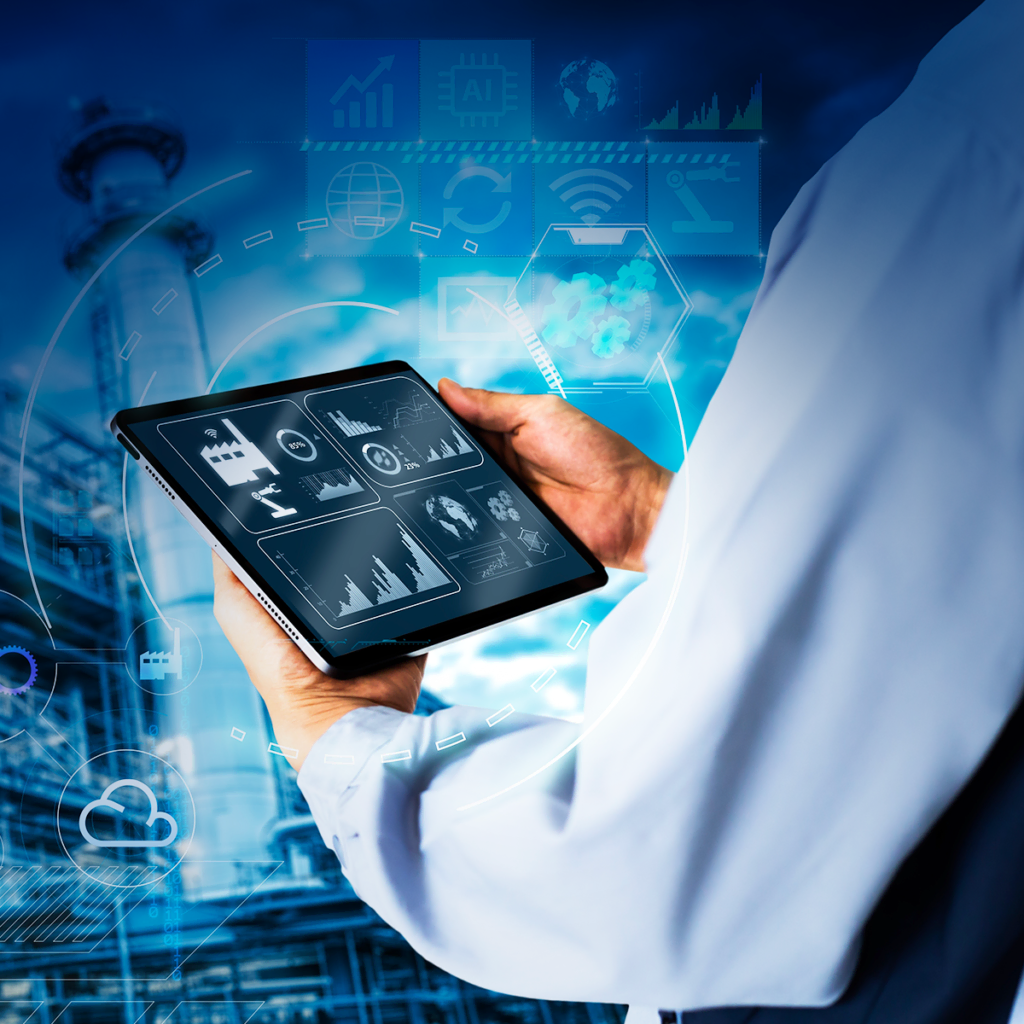 Une personne en chemise blanche tient une tablette affichant des analyses de données et des graphiques industriels, avec une superposition d'interface numérique et une usine en arrière-plan, symbolisant l'industrie intelligente et l'intégration technologique.