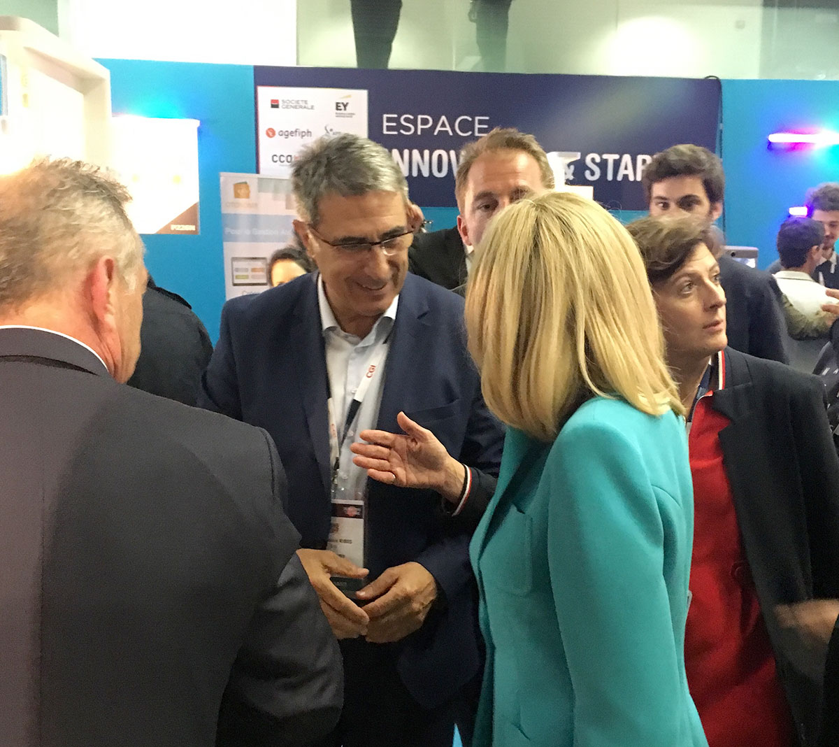 Plusieurs personnes en tenue professionnelle discutent lors d'un événement professionnel à Paris, avec en arrière-plan un panneau indiquant ESPACE INNOV et START, reflétant l'atmosphère animée et concentrée du Salon du Handicap.