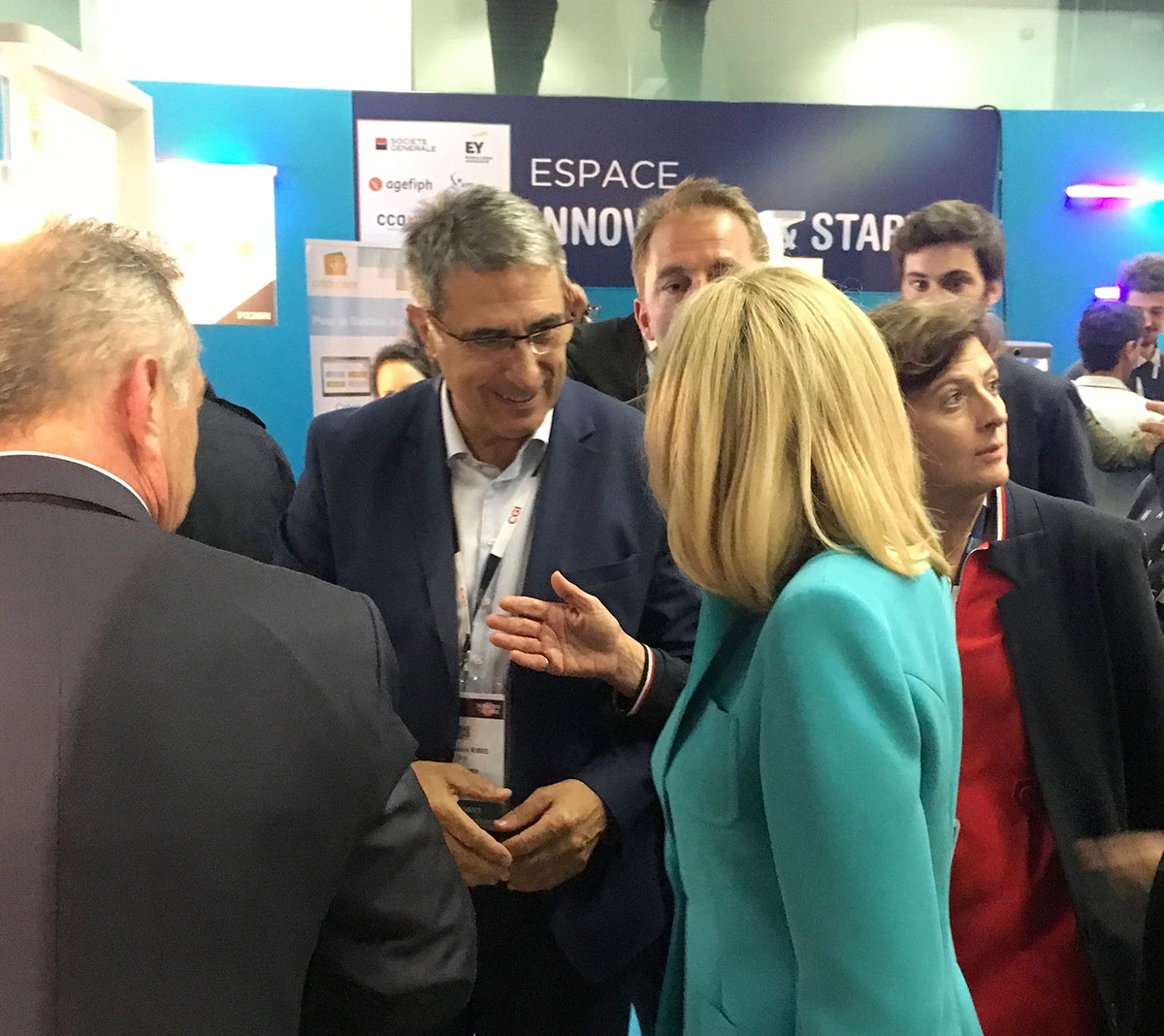Plusieurs personnes en tenue professionnelle discutent lors d'un événement professionnel à Paris, avec en arrière-plan un panneau indiquant ESPACE INNOV et START, reflétant l'atmosphère animée et concentrée du Salon du Handicap.