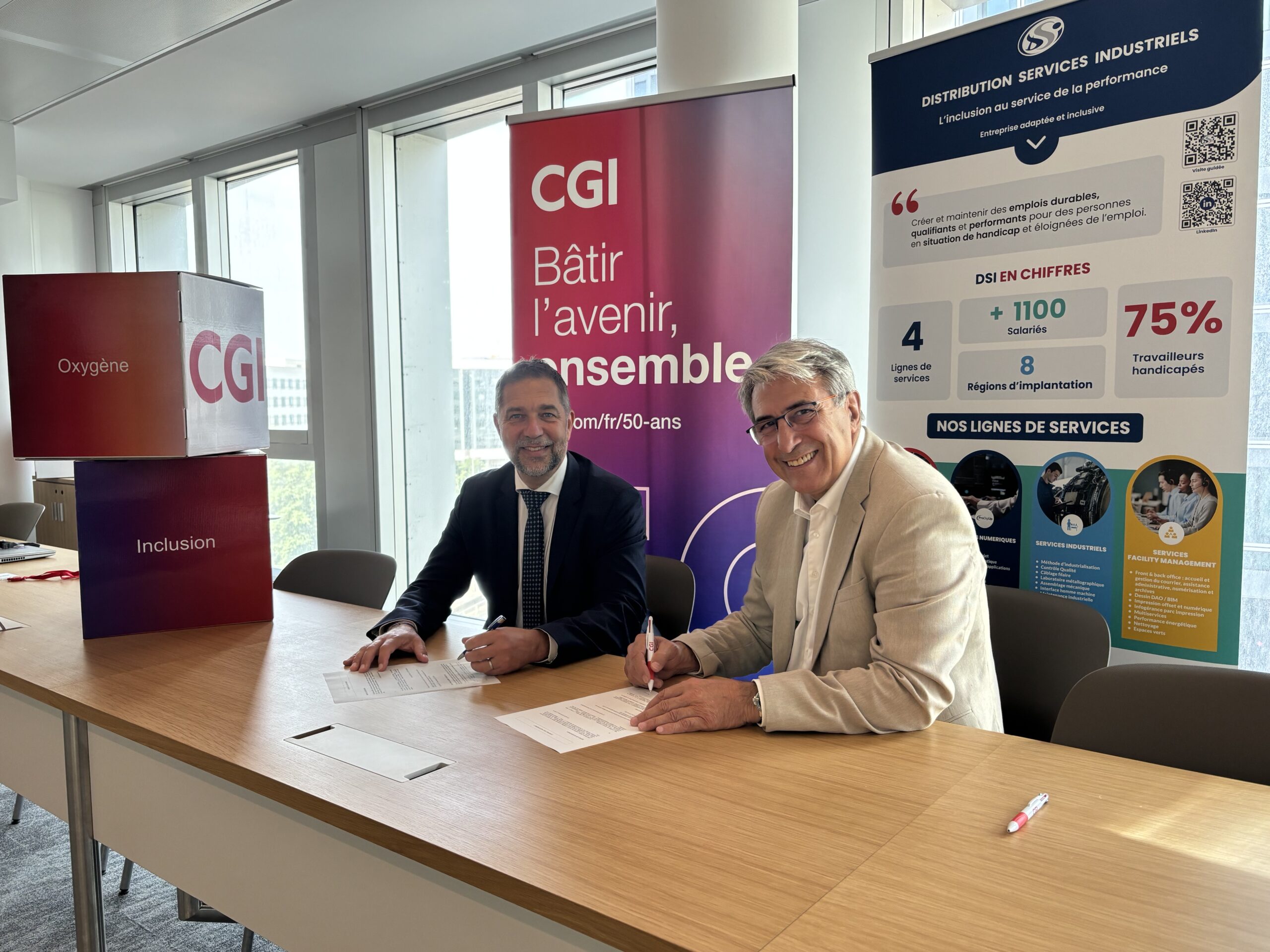 Deux hommes en costume sont assis à une table ; ils sourient et signent des documents. Derrière eux, on aperçoit des bannières aux couleurs de CGI et de DSI, ainsi que des cubes empilés sur lesquels sont inscrits « Oxygène » et « Inclusion ». Un espace de bureau lumineux doté de grandes fenêtres.